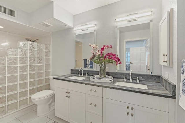 bathroom featuring tile patterned flooring, vanity, toilet, and walk in shower