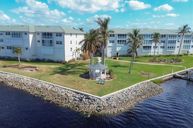 surrounding community with a water view and a lawn