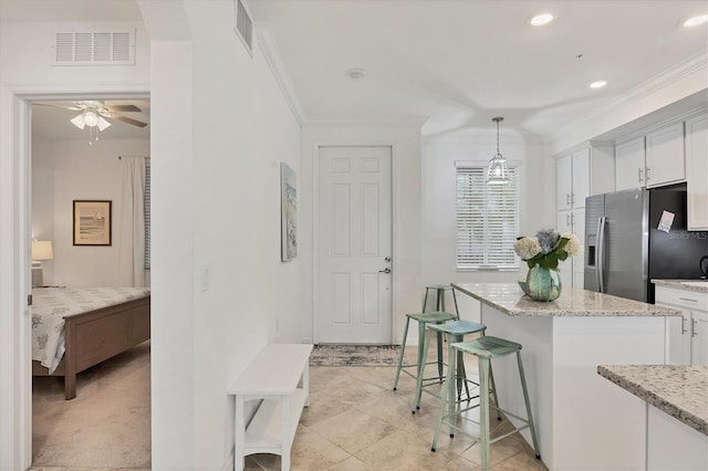 kitchen featuring white cabinets, hanging light fixtures, a kitchen island, and stainless steel fridge