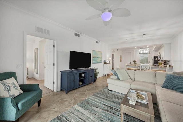 living room featuring light tile patterned flooring, ceiling fan with notable chandelier, and crown molding