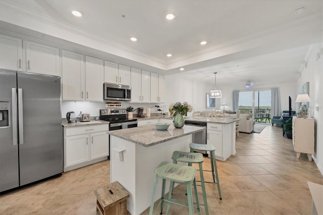 kitchen featuring light stone counters, stainless steel appliances, white cabinetry, decorative light fixtures, and a center island