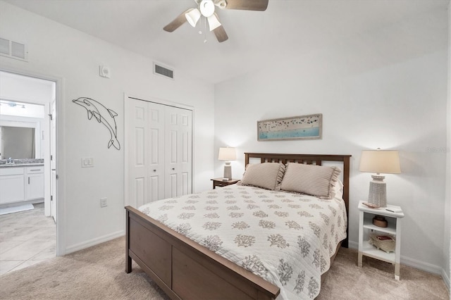 bedroom featuring light colored carpet, ceiling fan, connected bathroom, and a closet