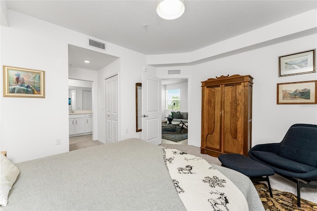 bedroom with connected bathroom, light colored carpet, and a closet