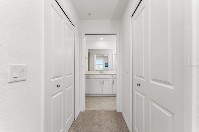 corridor with light carpet and sink