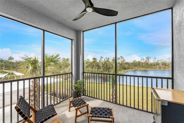 sunroom with ceiling fan and a water view