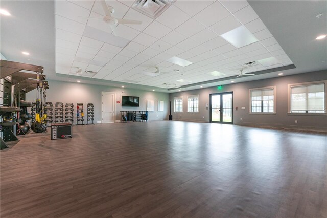 workout room with a raised ceiling, ceiling fan, french doors, and dark wood-type flooring