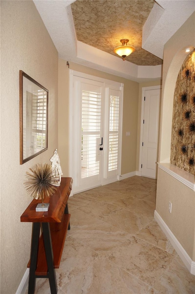 doorway with a textured ceiling and a raised ceiling