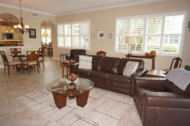 living area with a chandelier, ornamental molding, arched walkways, plenty of natural light, and baseboards