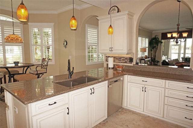 kitchen featuring dishwasher, a sink, a chandelier, dark stone countertops, and plenty of natural light