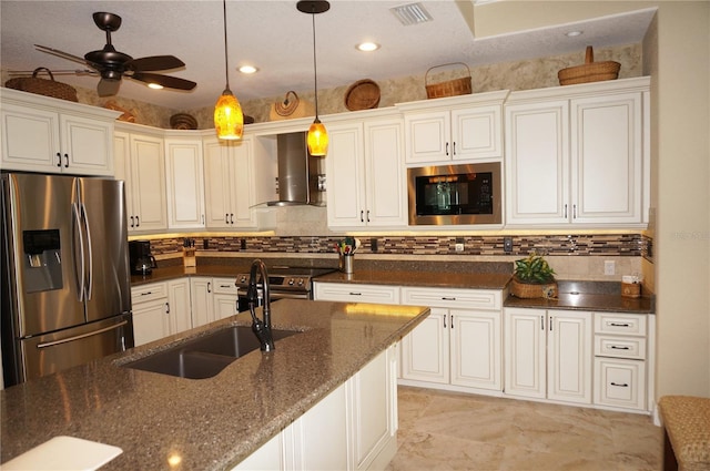 kitchen featuring stainless steel appliances, wall chimney exhaust hood, a sink, backsplash, and pendant lighting