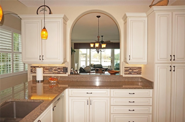 kitchen with dark stone counters, hanging light fixtures, decorative backsplash, and plenty of natural light