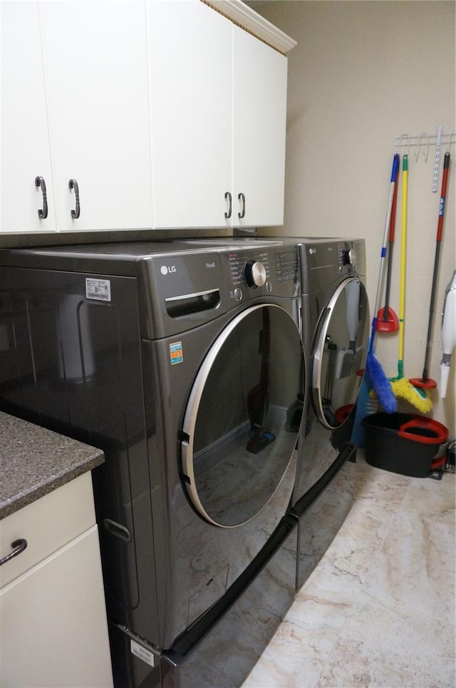 clothes washing area with washing machine and dryer and cabinets