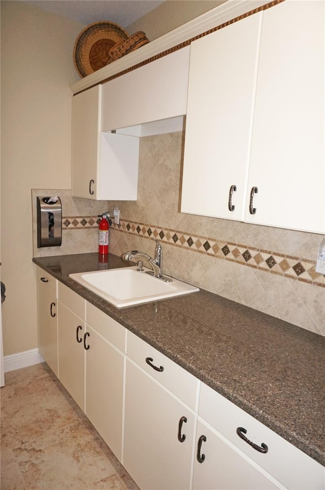 kitchen with dark stone countertops, white cabinetry, sink, and decorative backsplash