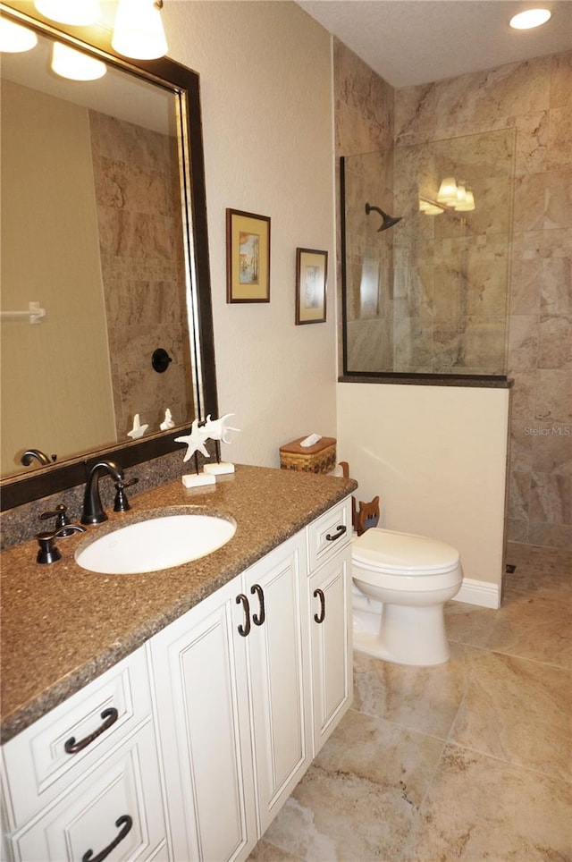 bathroom featuring toilet, vanity, and tiled shower