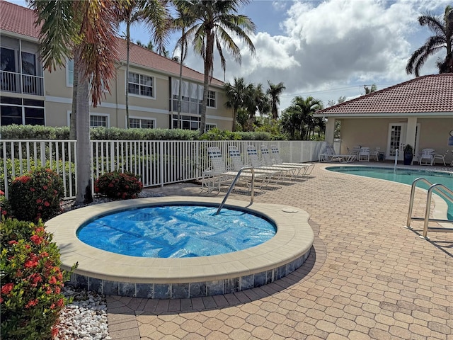 community pool with a community hot tub, fence, and a patio area