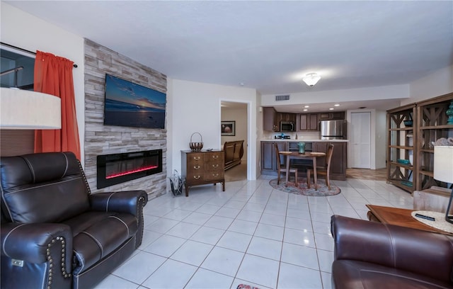 living room with a stone fireplace and light tile patterned flooring