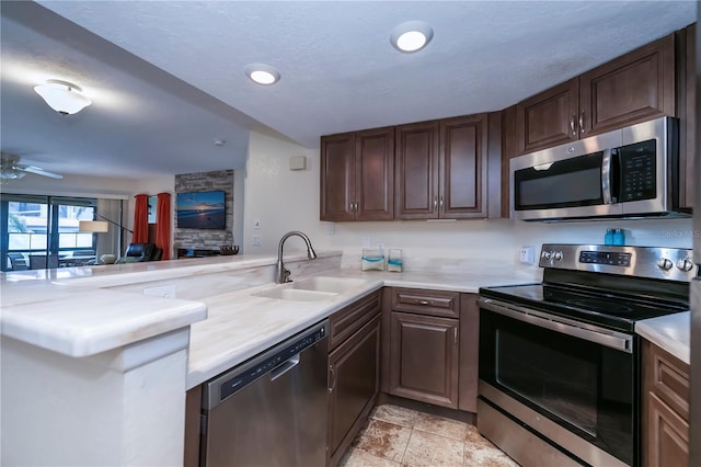 kitchen featuring sink, light tile patterned floors, dark brown cabinets, kitchen peninsula, and stainless steel appliances