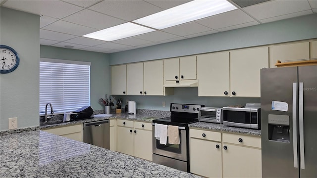 kitchen featuring cream cabinetry, appliances with stainless steel finishes, a drop ceiling, and sink