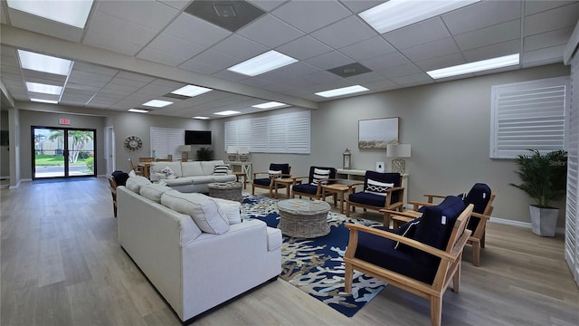 living room featuring light hardwood / wood-style floors and a drop ceiling