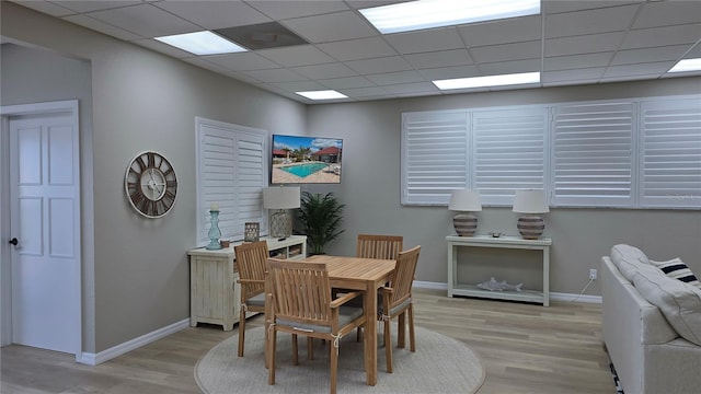 dining area featuring a paneled ceiling and light hardwood / wood-style flooring