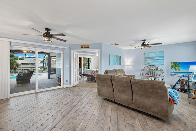 living room with light wood-type flooring, french doors, and ceiling fan