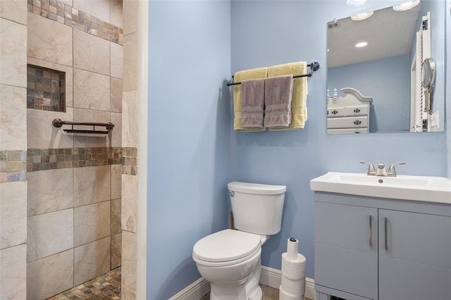 bathroom with vanity, toilet, and tiled shower