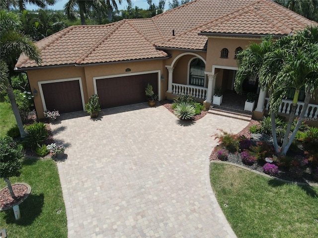 mediterranean / spanish-style house with a garage and covered porch