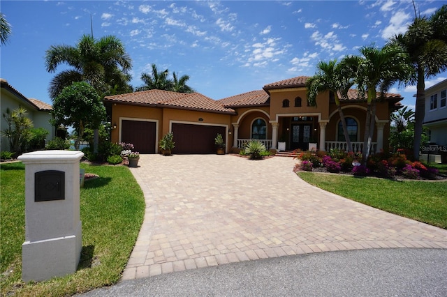 mediterranean / spanish home featuring a porch, a garage, and a front yard