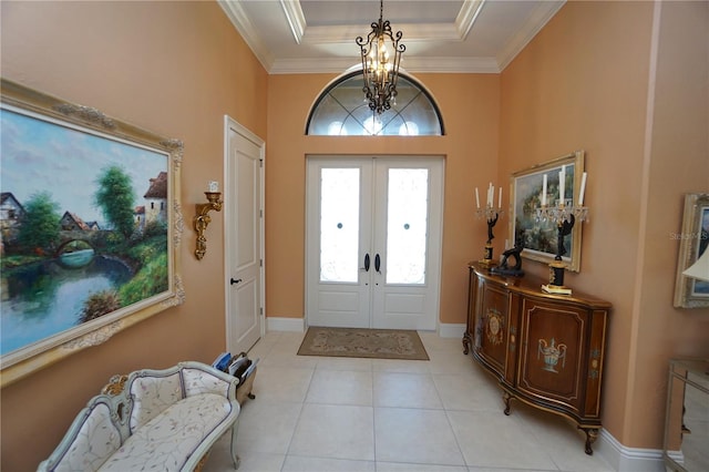 tiled foyer with french doors, a tray ceiling, an inviting chandelier, and crown molding