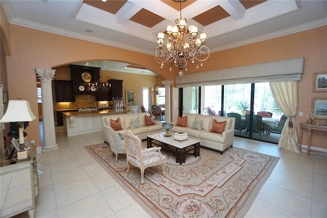 tiled living room with decorative columns, crown molding, a chandelier, and coffered ceiling