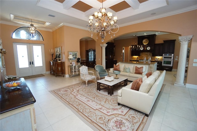 interior space featuring ornate columns, ornamental molding, a high ceiling, and french doors