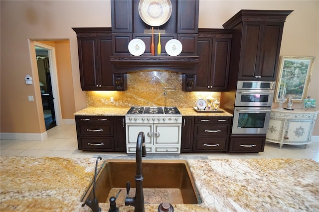 kitchen featuring dark brown cabinetry, sink, light tile patterned floors, and appliances with stainless steel finishes