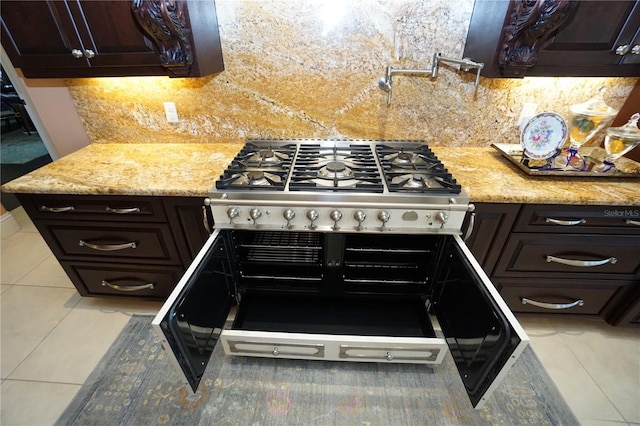 kitchen featuring stainless steel range, decorative backsplash, and dark brown cabinetry