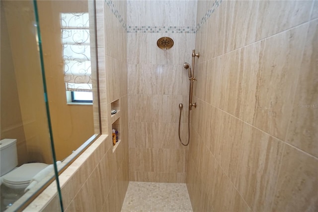 bathroom featuring toilet and a tile shower