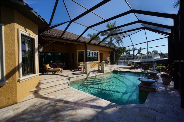 view of swimming pool featuring glass enclosure, a patio area, and ceiling fan