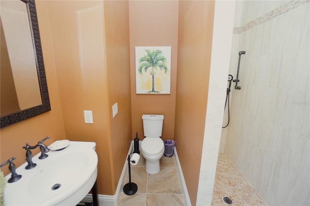 bathroom with toilet, sink, and tiled shower