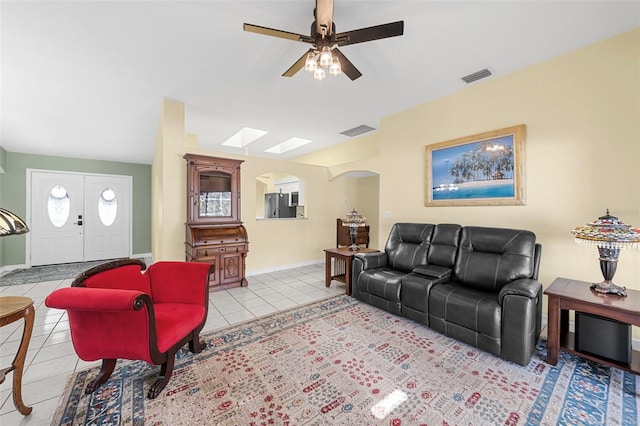 living room with a skylight, ceiling fan, and light tile patterned floors