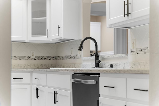 kitchen with tasteful backsplash, white cabinetry, sink, and stainless steel dishwasher