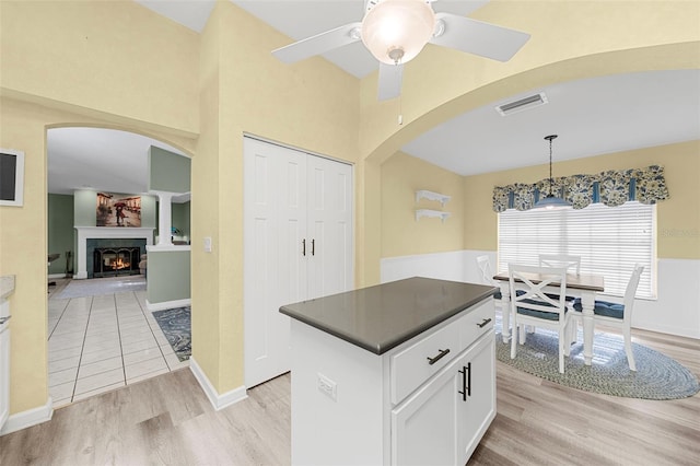 kitchen featuring white cabinetry, ceiling fan, pendant lighting, a kitchen island, and light wood-type flooring