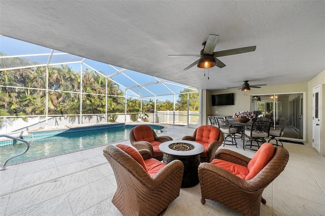 view of swimming pool with a lanai, an outdoor fire pit, ceiling fan, and a patio area