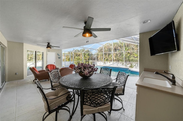 view of patio / terrace featuring glass enclosure, sink, and an outdoor kitchen