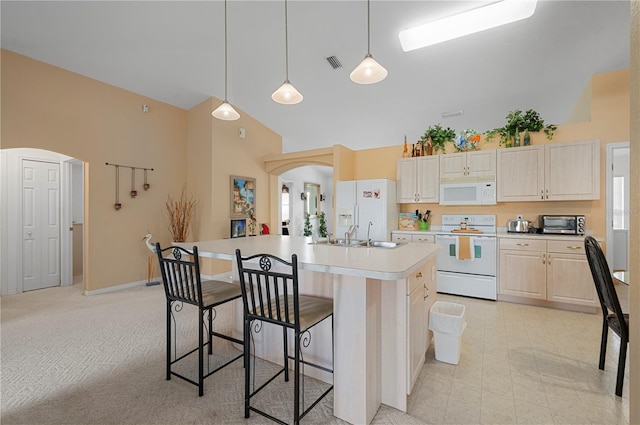 kitchen featuring a center island with sink, light carpet, a kitchen bar, high vaulted ceiling, and white appliances