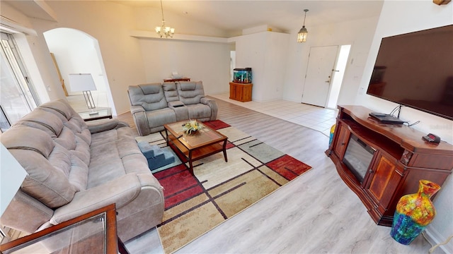 living room with vaulted ceiling, light hardwood / wood-style flooring, and an inviting chandelier