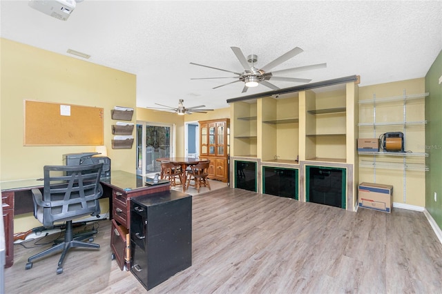 home office with hardwood / wood-style floors, ceiling fan, and a textured ceiling