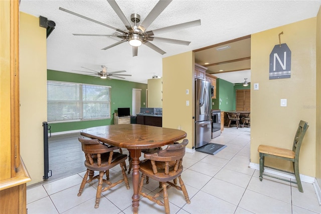 tiled dining space featuring a textured ceiling and ceiling fan