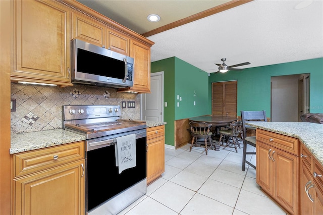 kitchen featuring stainless steel appliances, light tile patterned flooring, ceiling fan, and light stone counters