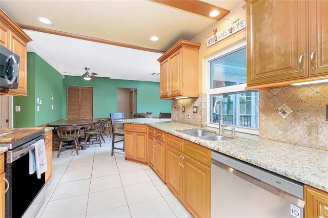 kitchen featuring stainless steel appliances, light stone counters, decorative backsplash, sink, and ceiling fan