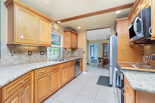 kitchen with backsplash, appliances with stainless steel finishes, light stone countertops, sink, and ceiling fan