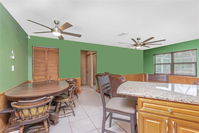 tiled dining space with ceiling fan and a textured ceiling