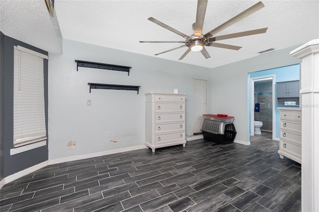 unfurnished bedroom featuring ceiling fan, connected bathroom, a textured ceiling, and dark hardwood / wood-style flooring